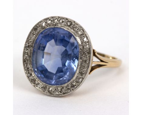 A sapphire and diamond cluster ring, the oval sapphire to a surround of diamonds in a galleried setting to an unhallmarked ye