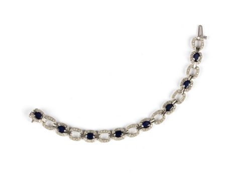 A sapphire and diamond bracelet, set with eight oval cut sapphires with oval interlocking links to a 14K white gold mount/see