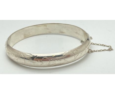 A 925 silver hinged bangle with half engraved detail, complete with safety chain. Box clasp stamped 925. Band width approx. 1