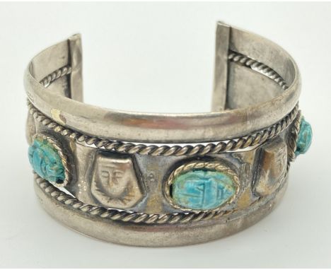 An Egyptian silver cuff bangle with carved stone set scarab beetle detail. Worn hallmarks to outer rims and each end of cuff.