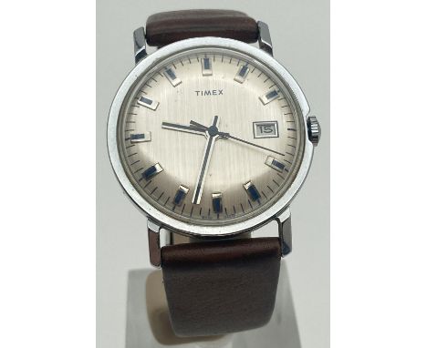 A vintage men's vintage wristwatch by Timex with brown leather strap. Silver tone brushed style face with blue hour markers a