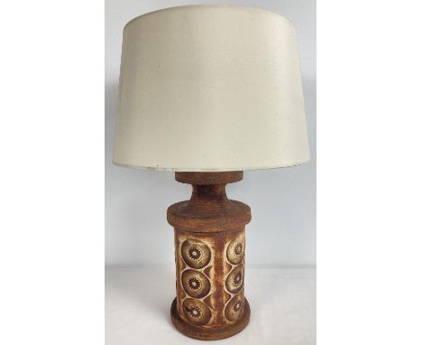 A vintage studio pottery lamp base with impressed circular design. Complete with cream coloured shade. Base approx. 27cm tall