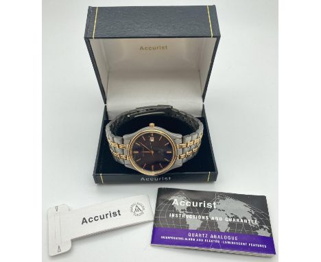 A boxed men's duo tone stainless steel bracelet wrist watch by Accurist. Black face with gold tone hour markers and hands. Se