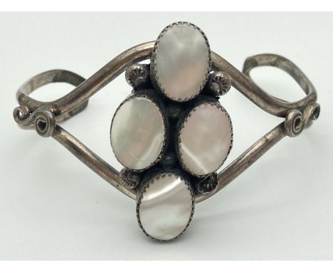 A white metal open style cuff bangle set with 4 oval pieces of mother-of-pearl. 