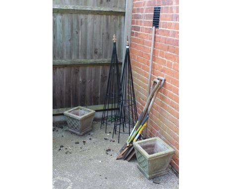 Two black metal garden obelisks for climbing plants, two weathered planters and garden tools