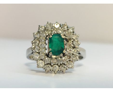 A 1970s Emerald and diamond cluster ring in 18ct white gold. The ring is set with 36 x brilliant cut diamonds with an estimat
