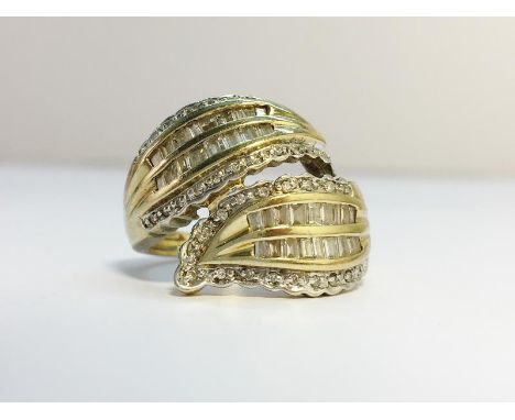 A Diamond crossover Ring set with baguettes and brilliant cut diamonds in 9ct yellow gold. Estimated total carat weight 0.9 c