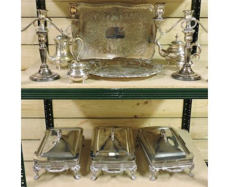 Two shelves of silver plated items, to include trays, candelabra and a set of three serving dishes