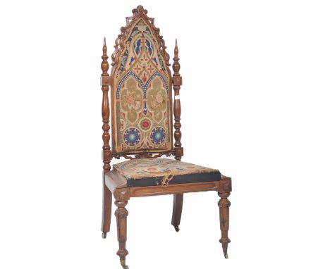 A 19th Century walnut ecclesiastical Gothic revival chair having a low tapestry seat and back with carved arched 'C' scroll a