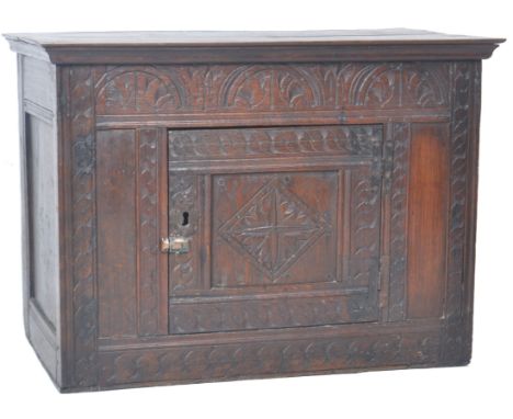 An 18th Century George III oak wall cupboard having a carved front set with small square door opening to reveal a spacious in