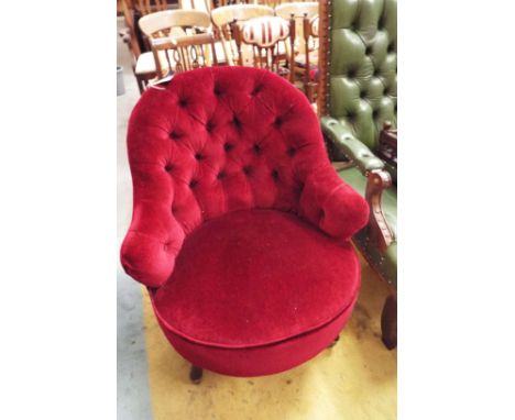 A late Victorian burgundy upholstered button-back tub shaped bedroom chair raised on squat cabriole supports with brass casto