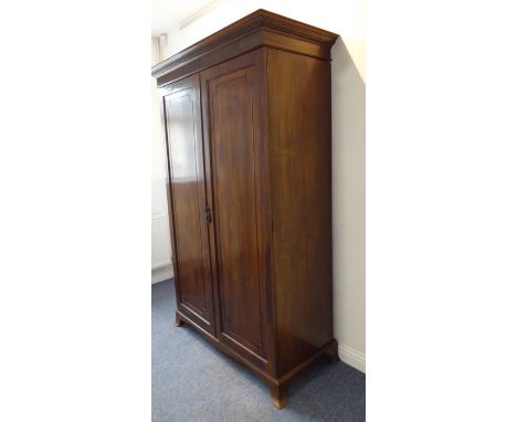 An 18th century-style (early) two-door mahogany wardrobe; dentil cornice above panelled doors and raised on ogee-style bracke