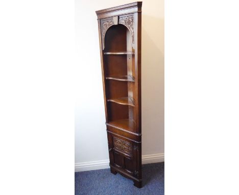 A reproduction oak freestanding corner cupboard of slim proportions; the cornice above two carved Tudor-style roses, three se