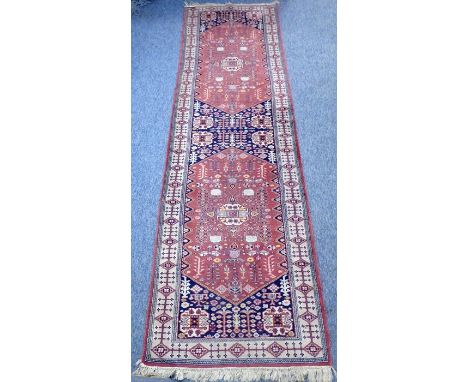 A hand-knotted Persian-style runner; two red lozenges against a dark ground and within a grey border having stylised repeatin