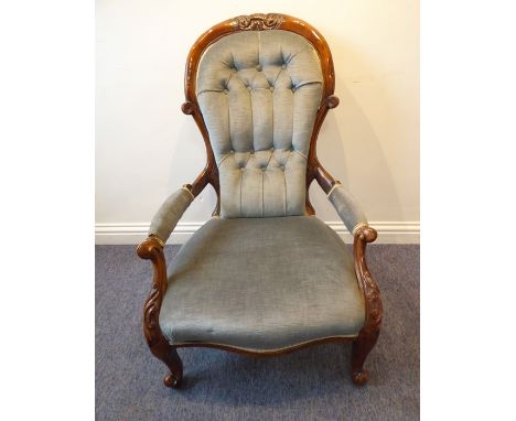 A mid-19th century mahogany show-wood frame and button-back upholstered spoon-back open armchair; scrolling arms with foliate