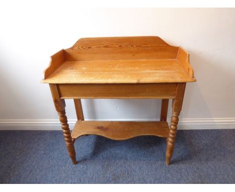 A 19th century pine washstand; the three-quarter galleried top above bobbin-turned style front legs united by a serpentine-fr