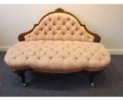A 19th century button-back upholstered and walnut-framed sofa; foliate carved back rail above similarly carved central frieze