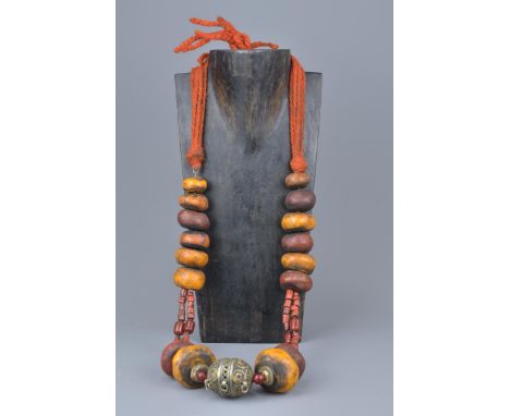 A large Moroccan amber resin and coral bead necklace with enamel silver metal pendant.