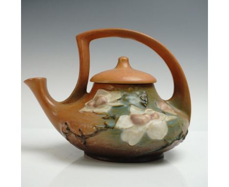 Charming lidded pottery teapot featuring a dramatic arching handle. his beautifully formed piece is decorated with creamy mag