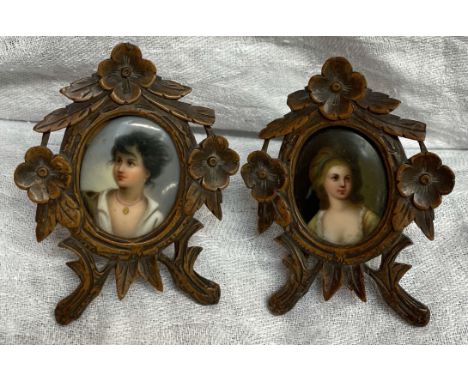 A pair of black forest easel frames carved with flowers and leaves together with a pair of porcelain portrait plaques