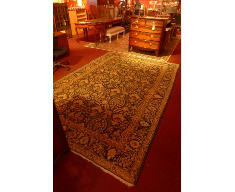 A Tabriz carpet decorated with floral designs on a navy blue field surrounded by one frieze and two running borders 