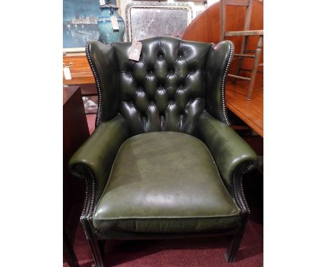 A green leather wingback armchair, with buttoned back and studded detail, with scrolling arms, raised on mahogany supports (i