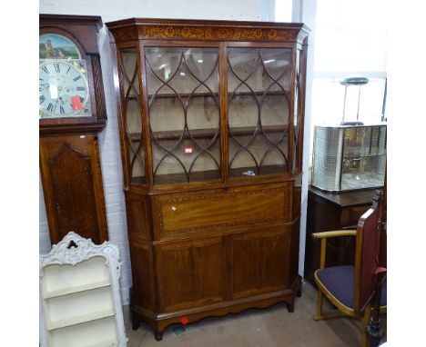 Circa 1900, a mahogany and satinwood-strung secretaire 2-section cabinet, of canted form, the top having lattice-glazed doors