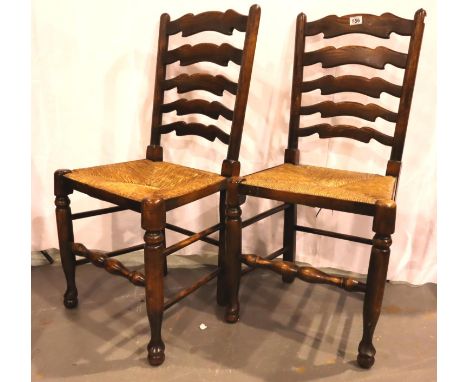 A pair of 20th century country oak kitchen chairs, with shaped ladder backs and rush seats. Not available for in-house P&amp;