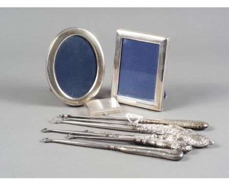 A silver pill box with hinged lid and engine turned decoration, seven silver handled button hooks and two silver picture fram