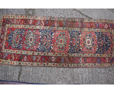 A Karafa runner with three floral medallions on a blue ground and triple bordered in shades of red, brown, cream, blue and na