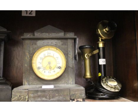 A rotary candlestick black and brass mounted telephone and a slate mantel clock with enamelled dial and Arabic numerals