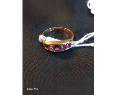 An early 20th century 18ct gold ruby and diamond ring, set three gradated round cut rubies, pair diamond chips between, plain