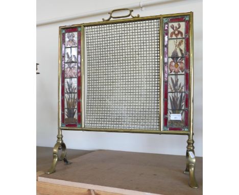 A brass fire screen with central wire panel and glass leaded floral panels to each side
