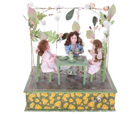 A hand wound musical automata Tea Party, German circa 1910, with three bisque head dolls with glass eyes and closed mouths, t