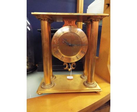 A French gilt metal mantle clock the drop dial having Roman numerals flanked by four Corinthium columns resting on a stepped 