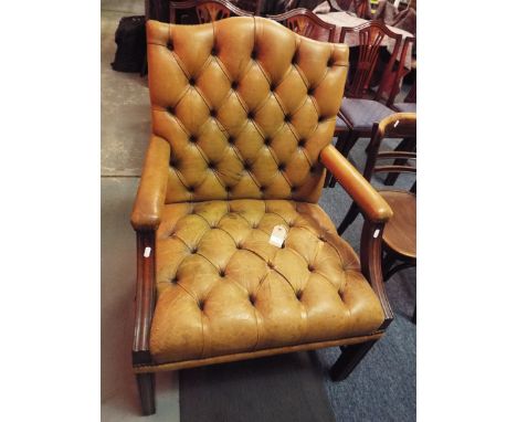 An Edwardian green leather button-back armchair