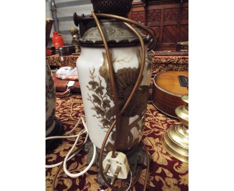 An Oriental ceramic oil lamp converted to electricity with applied gilt floral and bird decoration resting on an ornate scrol