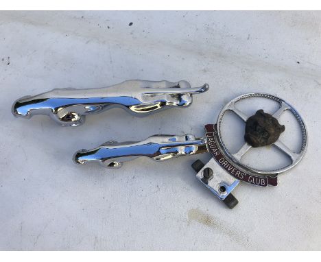 A Jaguar 'leaper' car mascot, one smaller and a Jaguar Drivers' Club part enamel badge.