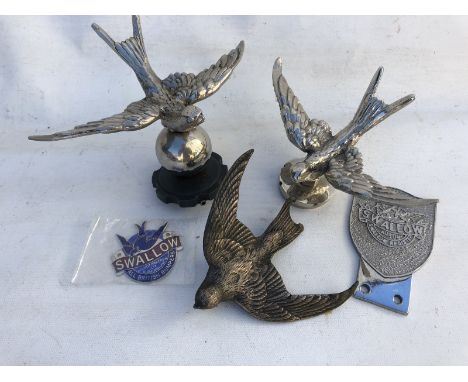 Three Austin 7 Swallow car mascots, an Austin 7 Swallow Register car badge and a Swallow enamel badge.