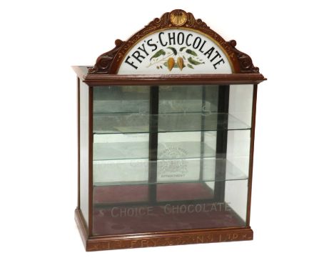 A Fry’s Chocolate walnut display cabinet,early 20th century, the arched parcel gilt pediment enclosing a Fry's Chocolate hail