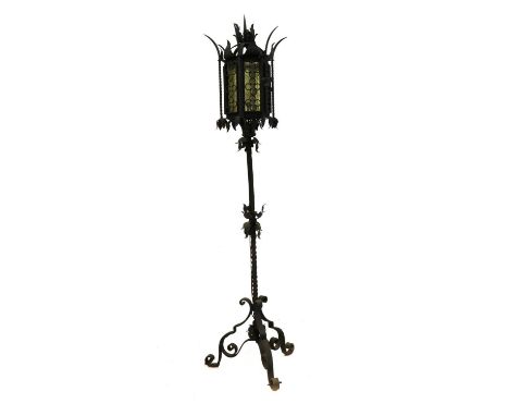 An Arts and Crafts wrought iron standard lamp, early 20th century, with six panelled glass shades, raised on a tripod base,17