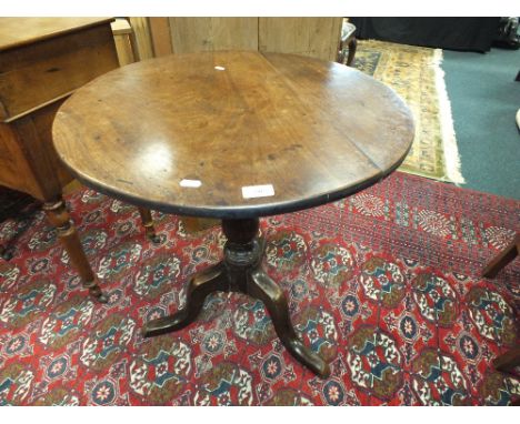 An early 19th century mahogany tripod table, the circular top on a baluster column and three down curved legs, 67cm diameter,