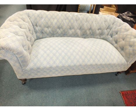 An Edwardian Chesterfield style button back sofa, later blue upholstered and on ring turned walnut squat legs and later sheph