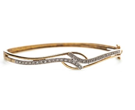 DIAMOND BANGLE, of waved form with crossover diamond set sections, the round brilliant cut diamonds totalling approximately 0