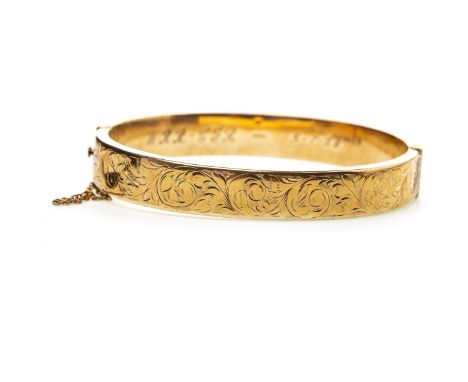 NINE CARAT GOLD BANGLE, with engraved scrolling decoration to the front panel, 63mm inner diameter, with safety chain, 14g
