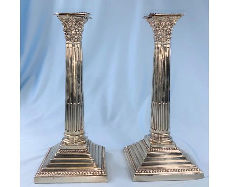 A hallmarked silver pair of candlesticks with Corinthian columns on weighted square stepped bases, London 1901, height 25.5 c