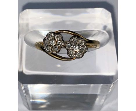 A yellow metal crossover dress ring set with twin 7 stone diamond flowerhead clusters, stamped 18ct size 'M' 2.8gms -&nbsp;So