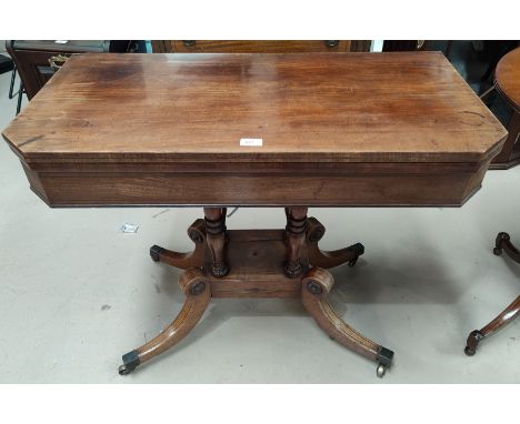 An early 19th century mahogany card table with canted foldover top, on 4 turned columns, splay feet and castors 