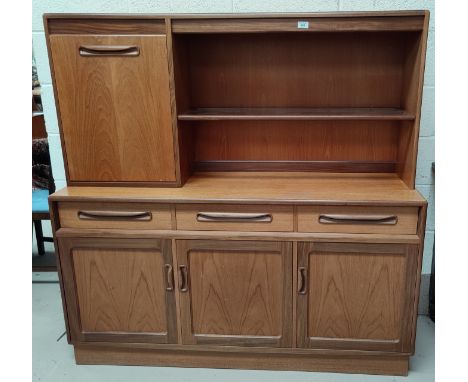 A mid 20th century teak G-Plan side unit having 3 cupboards, 3 drawers, pull down cupboard above with single shelf height 142