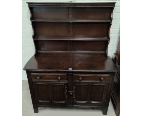 An Ercol dark oak Welsh dresser with 2 height delft rack over 2 cupboards and 2 drawers 